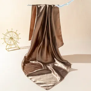 Detailed view of elegant brown satin square scarf draped gracefully on display hook.