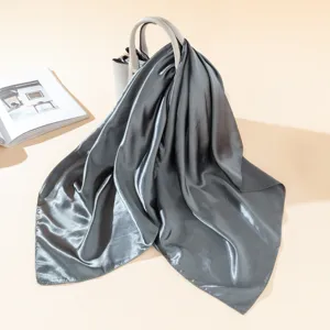 Detailed view of a glossy dark grey silk square scarf draped gracefully over a handbag.