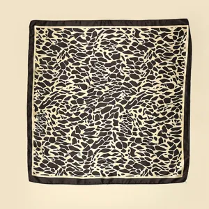 Detailed shot of abstract animal print silk scarf showing fine texture and dark border design.