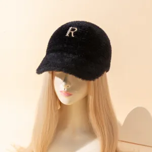 Detalle gorra visera felpa negra, decoración letra R stras, sombrero moda invierno cálido.