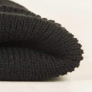 Vue en gros plan du détail du tissu du bonnet en tricot noir, montrant texture et chaleur.