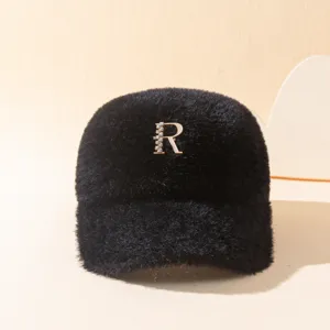 Primer plano detalle de la gorra de felpa negra con letra de pedrería brillante.