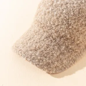 Primer plano de gorra visera de felpa teddy caqui con textura rizada suave para exteriores.
