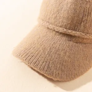 Primer plano detallado de una gorra visera de punto camello con textura fina y trenzado.