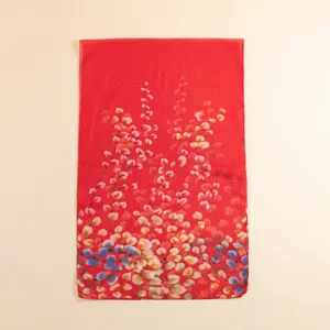 Gros plan d'un foulard en soie rouge vif avec un délicat imprimé floral coloré, texture légère.