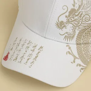 Detail shot of white baseball cap featuring gold dragon print and calligraphy design.