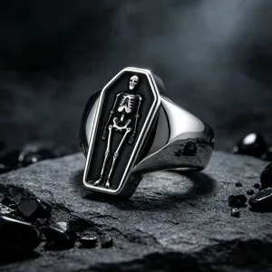 Close up detail of gothic punk coffin skeleton ring, stylish stainless steel black stone backdrop.