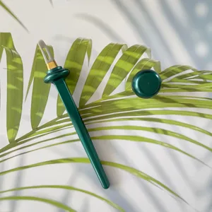 Detailed view of the green silicone eyeliner tool on palm leaf showing closeup texture.