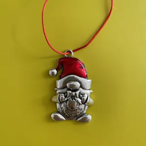 Close-up detail of the metal Christmas gnome ornament with red enamel hat and hanging string.
