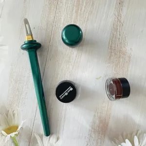 Silicone eyeliner brush detail view with cream jar and cap on rustic wooden surface showcase.