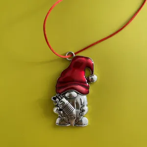 Detailed close-up of a festive Christmas gnome metal pendant with red enamel hat and hanging string.