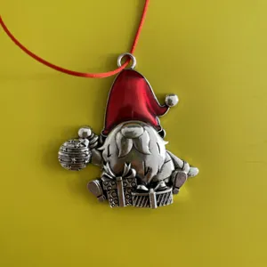 Close-up detail shot of a cute metal Christmas gnome ornament featuring a vibrant red hat.