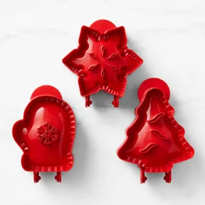 Detail shot of red plastic Christmas cookie and pie molds in snowflake, mitten, tree shapes.