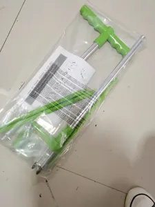 Handheld weed puller tool with long aluminum handle and comfortable green plastic grip.