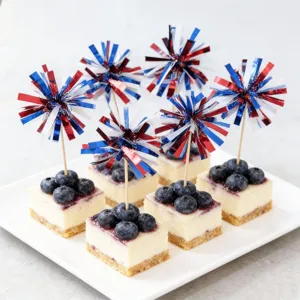 Close up shot of patriotic tinsel firework toothpick toppers on cheesecake bites for party.