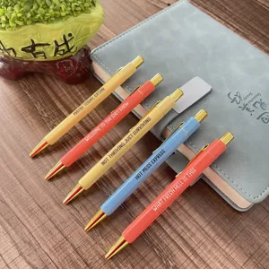 Detailed close-up shot of colorful novelty quote ballpoint pens with funny text on wooden table.