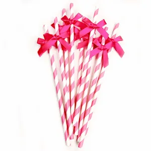 Decorative pink and white striped paper straws featuring elegant bright ribbon bows for party.