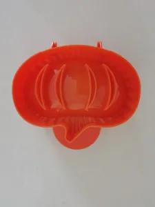 Detail view of the orange plastic hand pie mold featuring embossed ribbed lines for baking.