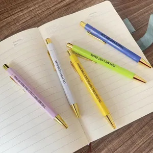 Detailed close-up of colorful metal clip ballpoint pens with funny office quotes.