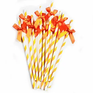 Detail view of decorative paper drinking straws featuring vibrant orange bows for party setup.
