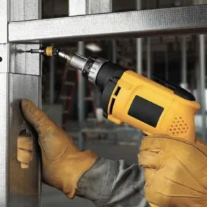Magnetic pivoting drill bit holder detail view showing screw driving application on metal framing.