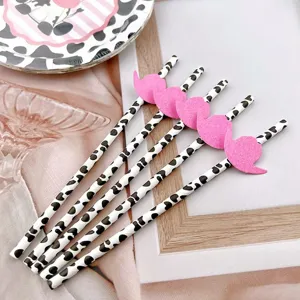 Close-up detail shot of creative cow print paper straws featuring cute pink felt hat decor for parties.