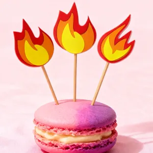 Detailed view of cute flame cake toppers with wooden sticks inserted in a colorful macaron.