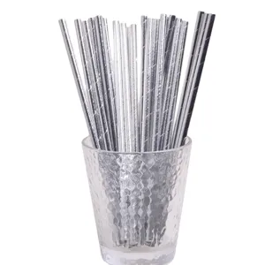 Gros plan détaillé de pailles à boire en papier argenté dans un verre transparent de fête.
