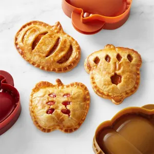 Detail view of autumn hand pie molds set with baked pastry samples on marble background.