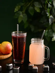 Paille en papier argentée en vue détaillée dans des verres avec glaçons et fruits.