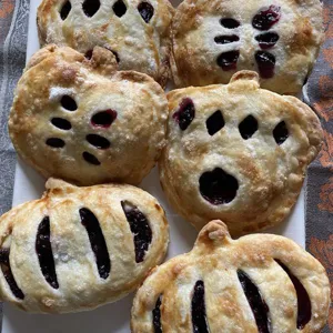 Detailed view of homemade autumn fruit pies and pumpkin pastries baked in molds for fall.