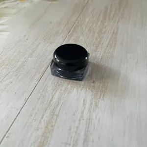 Detailed close-up of a compact cosmetic sample jar with a sleek black cap and clear base.