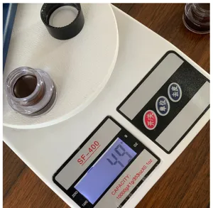 Detail view of brown gel eyeliner cream weight display on digital scale for makeup use.