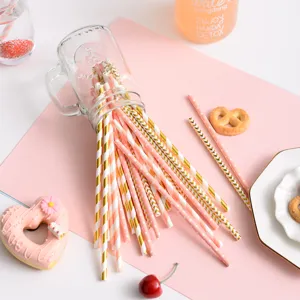 Close-up of pink and gold striped paper straws spilling out of a clear jar for party decor.