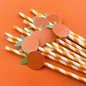 Primo piano dettagliato delle cannucce di carta arancione creative con decorazioni di frutta.