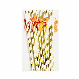 Gold and white striped paper straws with orange bow detail, perfect for party decor table