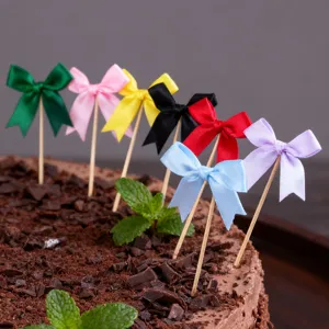 Close-up of colorful ribbon bow cake toppers inserted on chocolate cake for party decor.