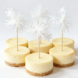 Detail shot of mini cheesecakes decorated with elegant white snowflake tassel cake toppers.