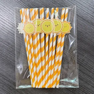 Close-up of orange and white striped paper straws with cute smiling sun decorations in a bag.