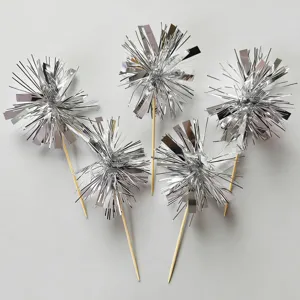 Close-up detail of silver tinsel cake toppers, sparkling metallic fringe firework picks for desserts.