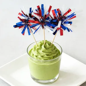 Detail shot of red white and blue tinsel firework picks decorating green dessert for celebration