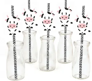 Cute cow paper drinking straws set with glass bottles for party decoration and beverage display.