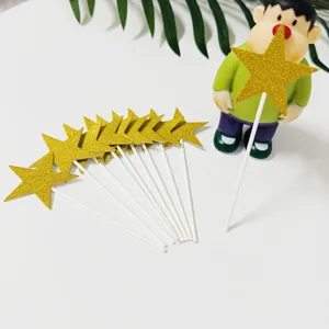 Nahaufnahme von goldenen Glitzerstern-Kuchendeckern mit weißen Stäben für Party-Dekoration.