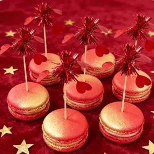 Red and gold macarons with heart tinsel picks for romantic Valentine's Day party decor.