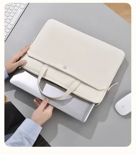 Primo piano dettagliato di una custodia per laptop beige con maniglie su una scrivania grigia.