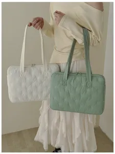 Vue détaillée du sac cabas matelassé pour ordinateur avec jolis nœuds brodés et anses.