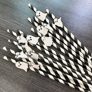 Detailed close-up shot of Halloween black and white striped paper straws with cute ghost cutouts.