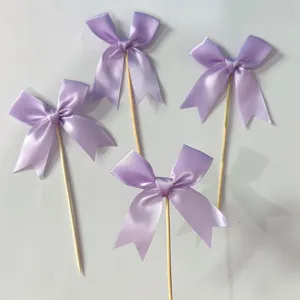 Detailed view of purple satin ribbon bow cake toppers, perfect for dessert party decor.