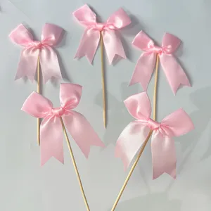 Pink satin ribbon bow cake toppers detail view, cute dessert decoration picks for party baking.