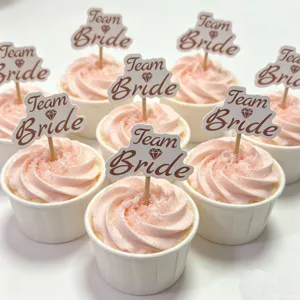 Vista dettagliata dei cake topper Team Bride con crema rosa per decorazione festa.